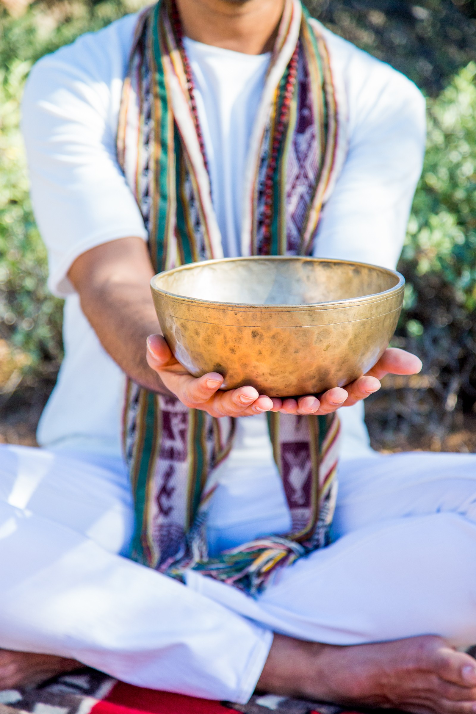 A hammered metal singing bowl held out in two hands